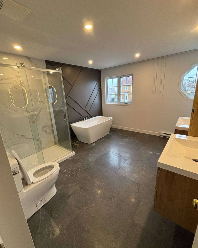 Salle de bain terminée avec douche vitrée et bain autoportant.